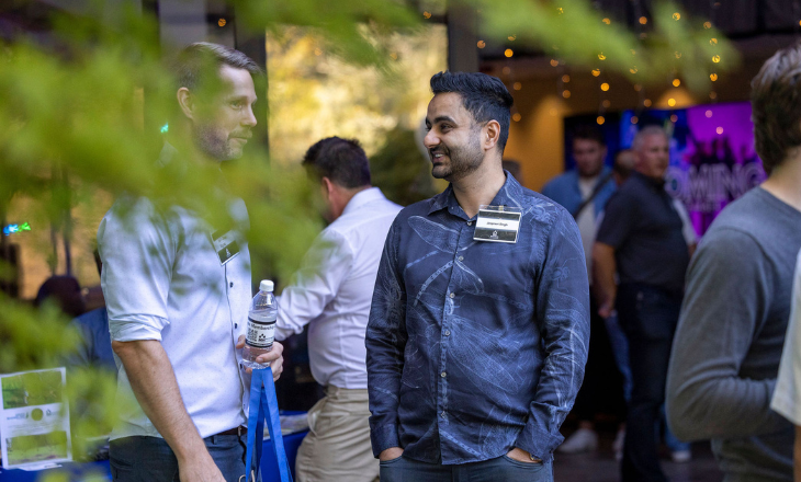 Two people talk admist a crowd at event.