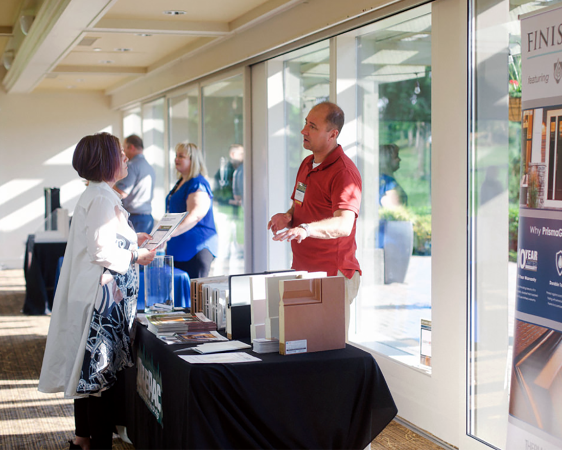 An OrePac representative shows samples of their different door products to an MBAKS member at an indoor event