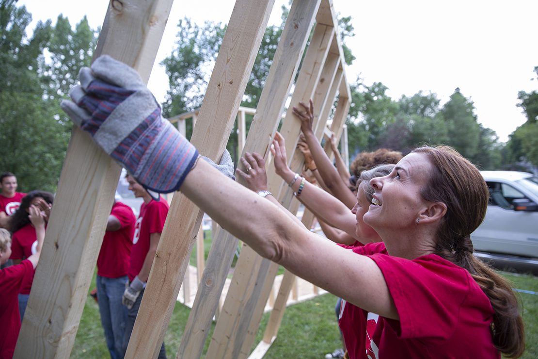 Female volunteer lifting house frame at construction site