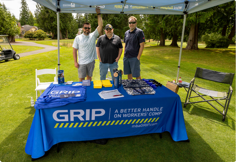 Three people at informational table on golf course.