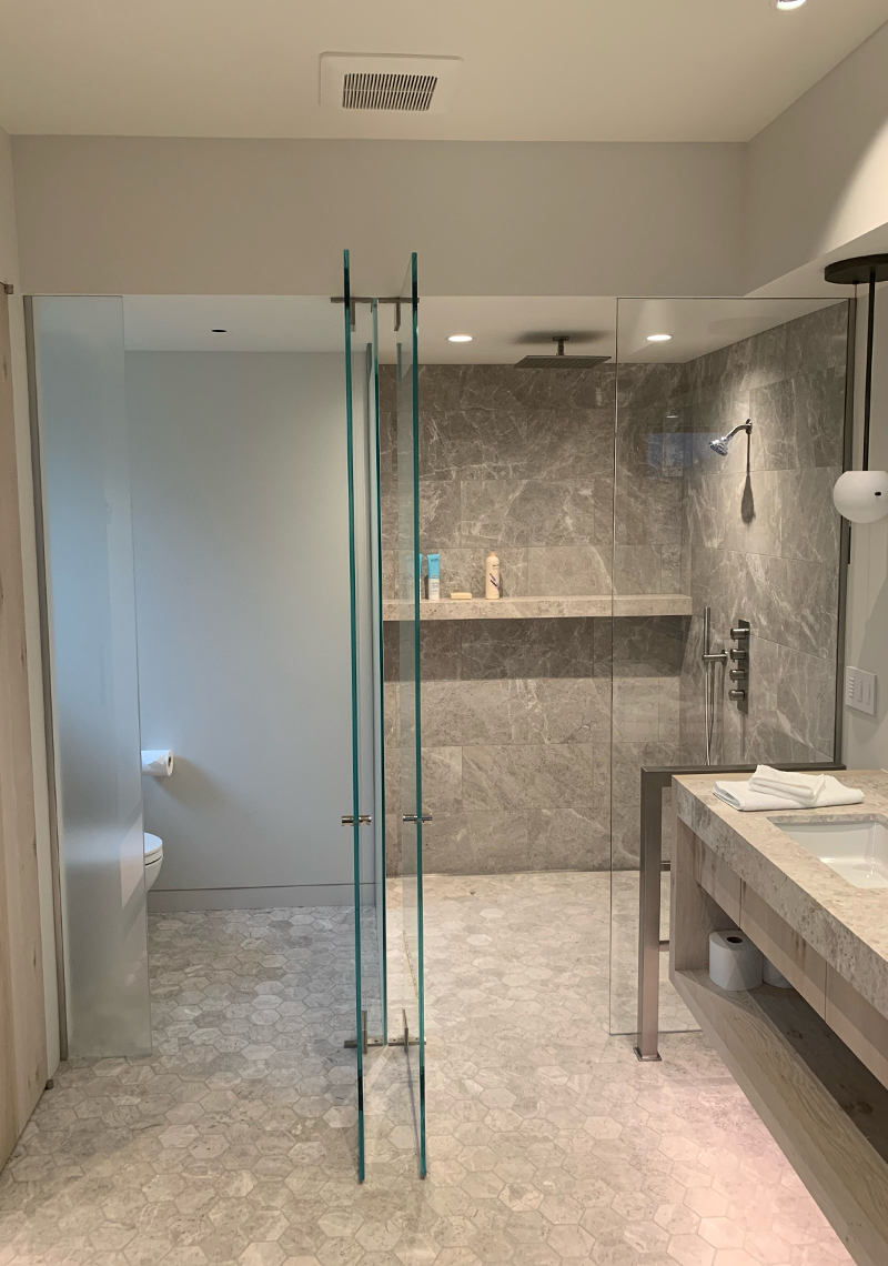 Custom glasswork courtesy Distinctive Glass. Highlights include shimmering glass shower walls and doors showcasing a minimalist rack wine room.