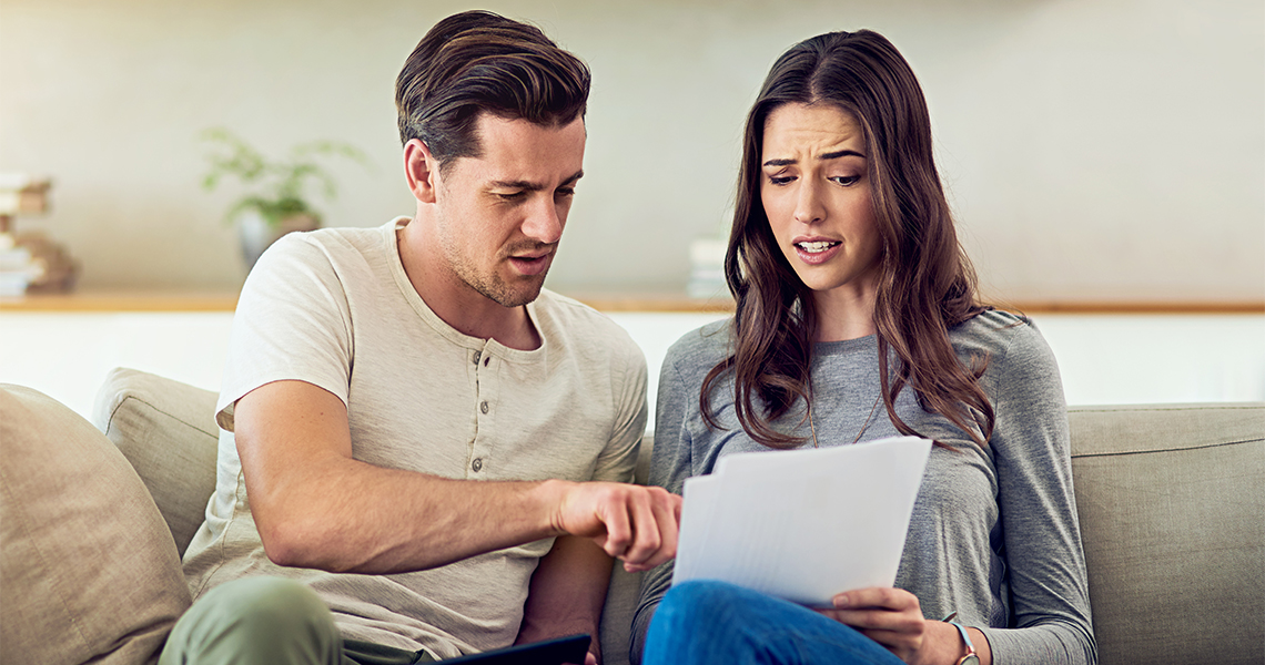 Young couple shocked looking at expensive bill