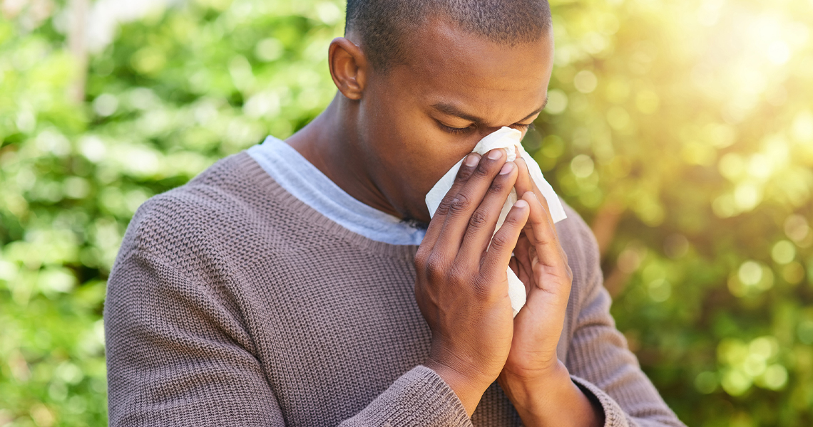 Young man blowing his nose outdoors