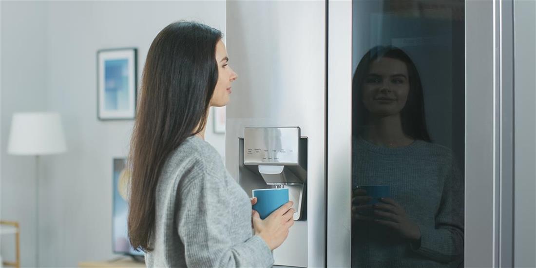 Woman stands in front of a fridge with a smart panel